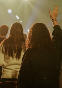 Group of people in front of a stage with hands raised in worship